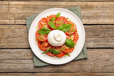 Photo of Tasty salad Caprese with mozzarella, tomatoes, basil and pesto sauce on wooden table, top view