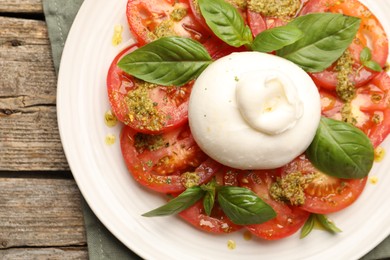 Photo of Tasty salad Caprese with mozzarella, tomatoes, basil and pesto sauce on wooden table, top view