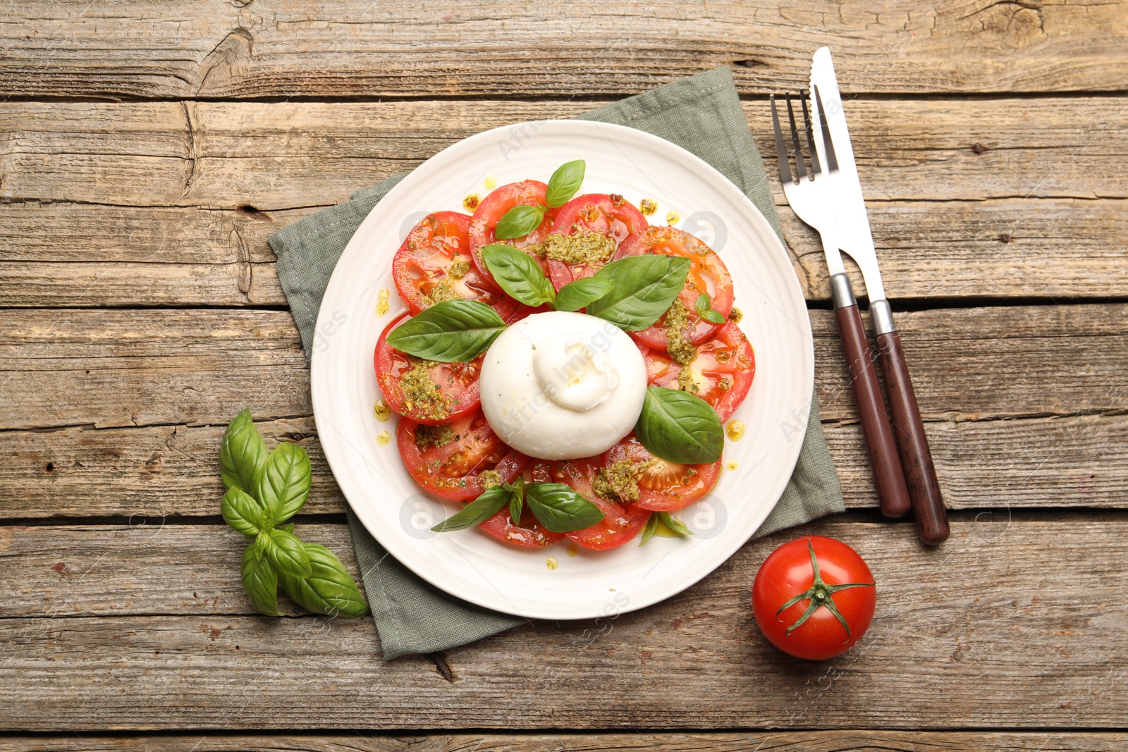 Tasty salad Caprese served with pesto sauce on wooden table, flat lay Photo of Tasty salad Caprese served with pesto sauce on wooden table, flat lay