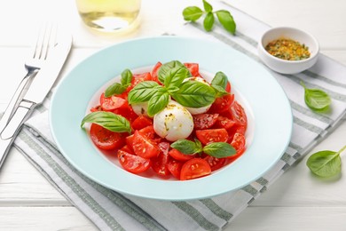 Photo of Tasty salad Caprese with mozzarella, tomatoes, basil and spices on white wooden table, closeup