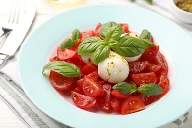 Photo of Tasty salad Caprese with mozzarella, tomatoes, basil and spices on table, closeup