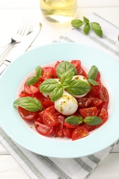 Photo of Tasty salad Caprese with mozzarella, tomatoes, basil and spices on white wooden table, closeup