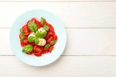 Photo of Tasty salad Caprese with mozzarella, tomatoes, basil and spices on white wooden table, top view. Space for text
