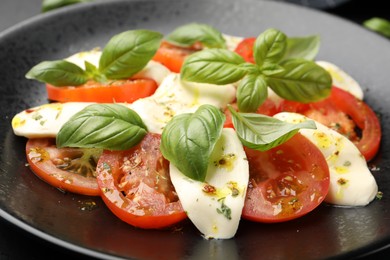 Photo of Tasty salad Caprese with mozzarella, tomatoes, basil and spices on table, closeup