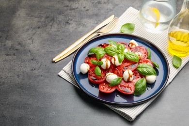 Photo of Tasty salad Caprese served with balsamic vinegar on grey table, closeup. Space for text