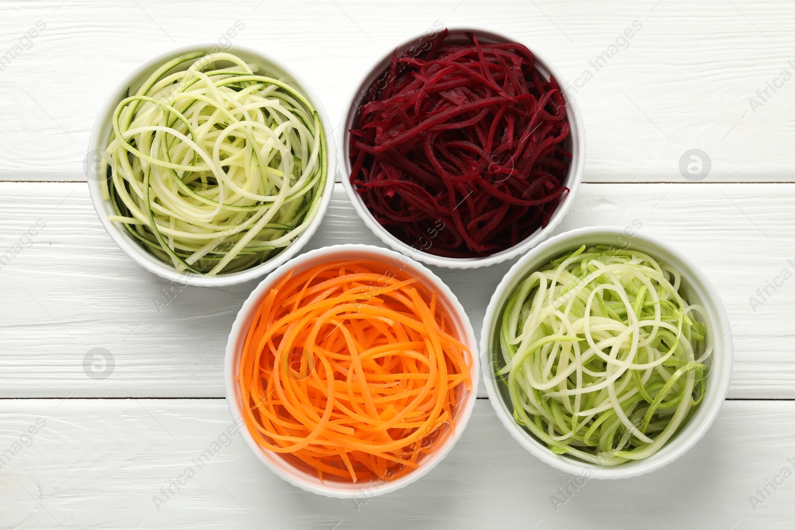 Different vegetable noodles in bowls on white wooden table, flat lay. Vegetarian dish Photo of Different vegetable noodles in bowls on white wooden table, flat lay. Vegetarian dish