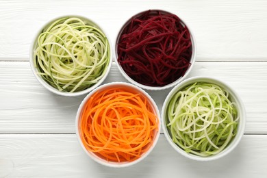 Photo of Different vegetable noodles in bowls on white wooden table, flat lay. Vegetarian dish