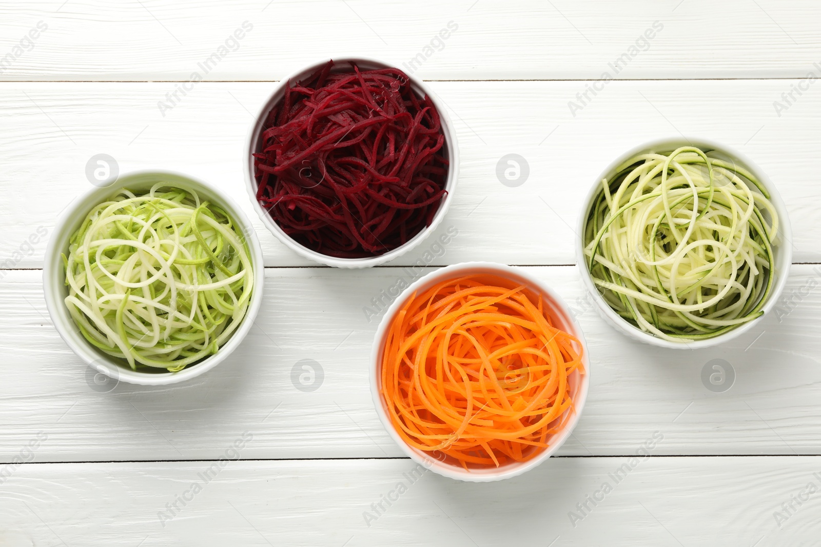 Photo of Different vegetable noodles in bowls on white wooden table, flat lay. Vegetarian dish