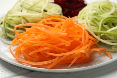 Photo of Different vegetable noodles on white wooden table, closeup. Vegetarian dish
