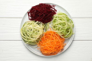 Photo of Different vegetable noodles on white wooden table, top view. Vegetarian dish