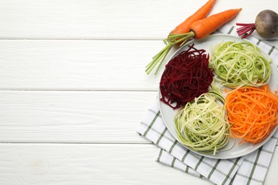 Photo of Vegetarian dish. Different vegetable noodles and fresh vegetables on white wooden table, flat lay. Space for text