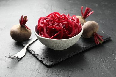 Photo of Raw beetroot noodles and fresh vegetables on black table, closeup. Vegetarian dish