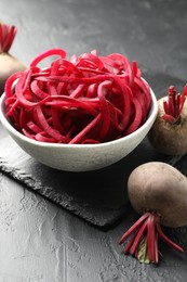 Photo of Raw beetroot noodles and fresh vegetables on black table, closeup. Vegetarian dish