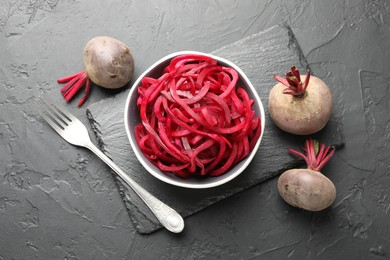 Photo of Raw beetroot noodles and fresh vegetables on black table, flat lay. Vegetarian dish