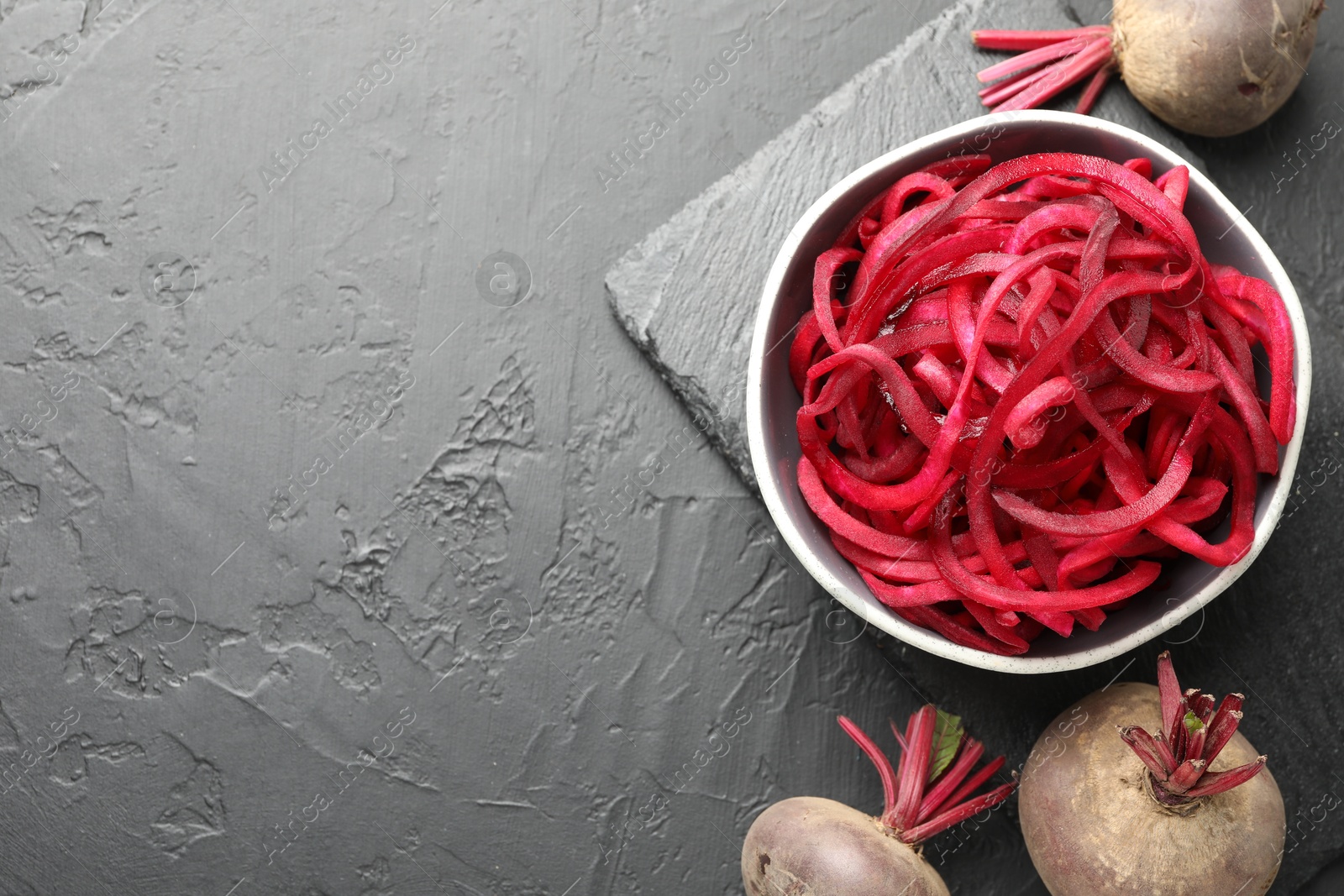 Vegetarian dish. Raw beetroot noodles and fresh vegetables on black table, flat lay. Space for text Photo of Vegetarian dish. Raw beetroot noodles and fresh vegetables on black table, flat lay. Space for text