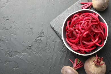 Photo of Vegetarian dish. Raw beetroot noodles and fresh vegetables on black table, flat lay. Space for text