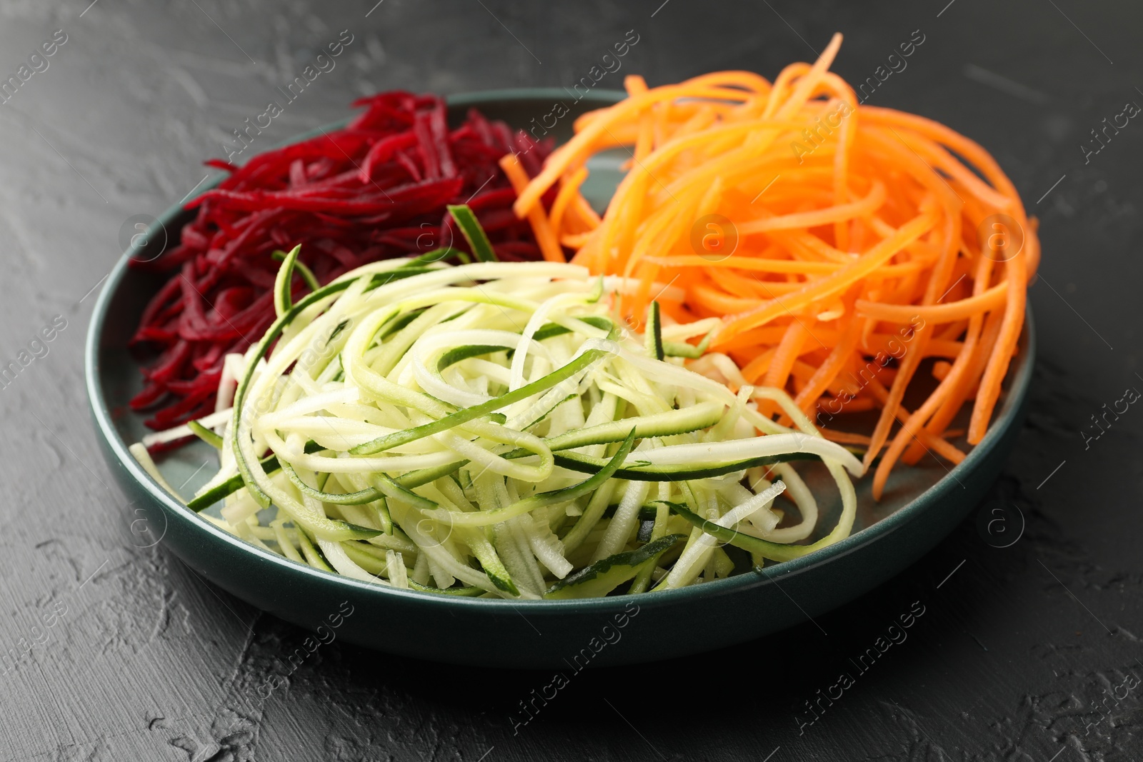 Photo of Different vegetable noodles on black table, closeup. Vegetarian dish