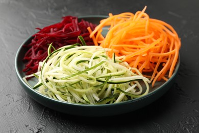 Photo of Different vegetable noodles on black table, closeup. Vegetarian dish