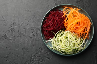 Photo of Vegetarian dish. Different vegetable noodles on black table, top view. Space for text