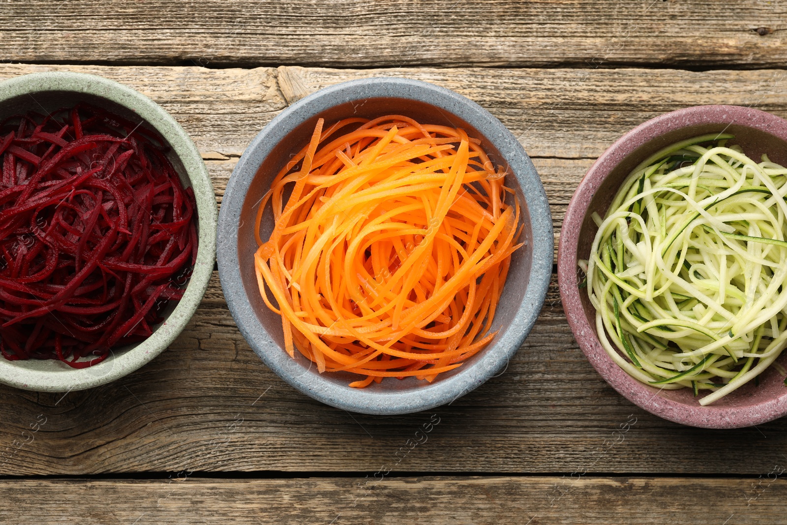 Photo of Different vegetable noodles in bowls on wooden table, flat lay. Vegetarian dish