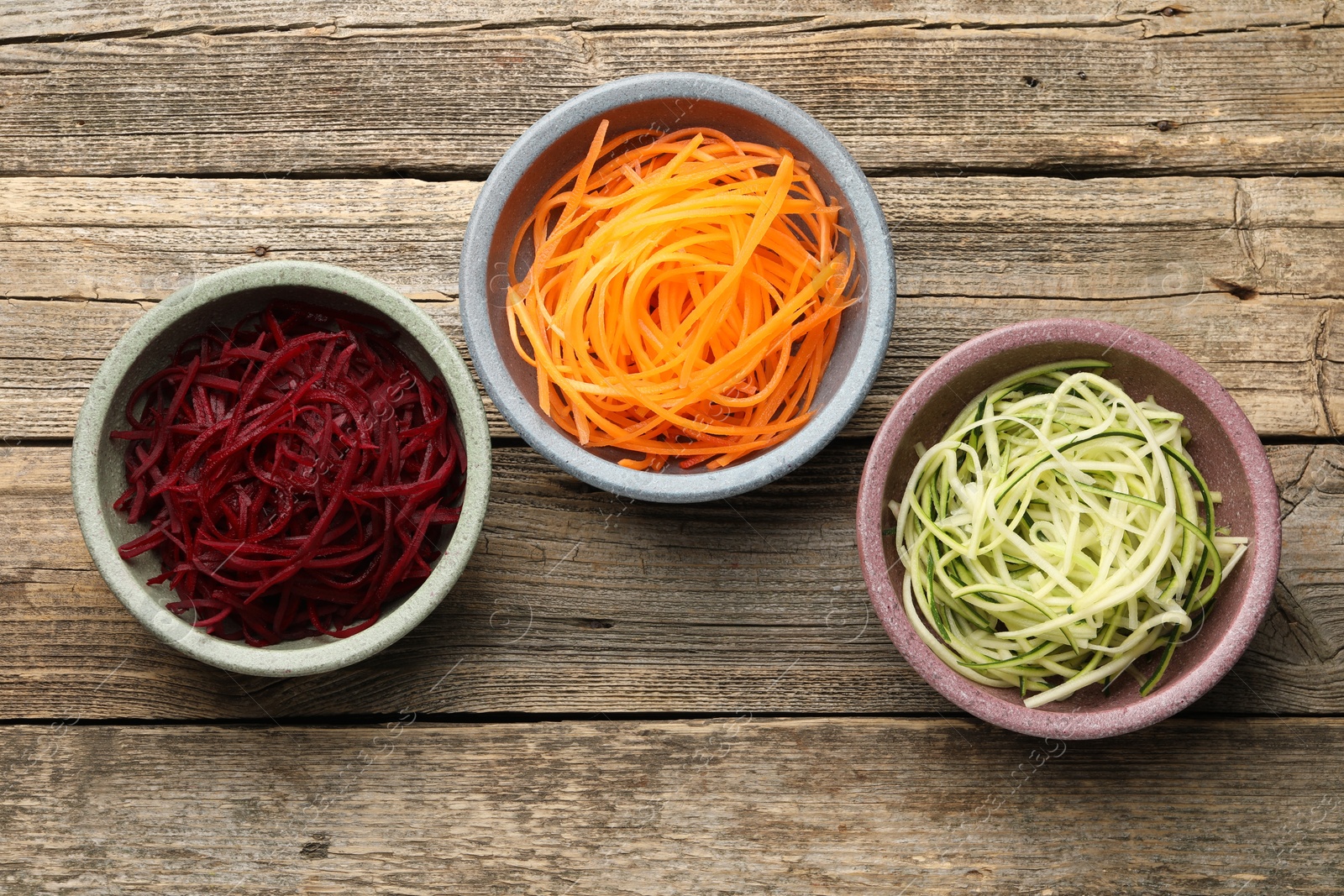 Different vegetable noodles in bowls on wooden table, flat lay. Vegetarian dish Photo of Different vegetable noodles in bowls on wooden table, flat lay. Vegetarian dish