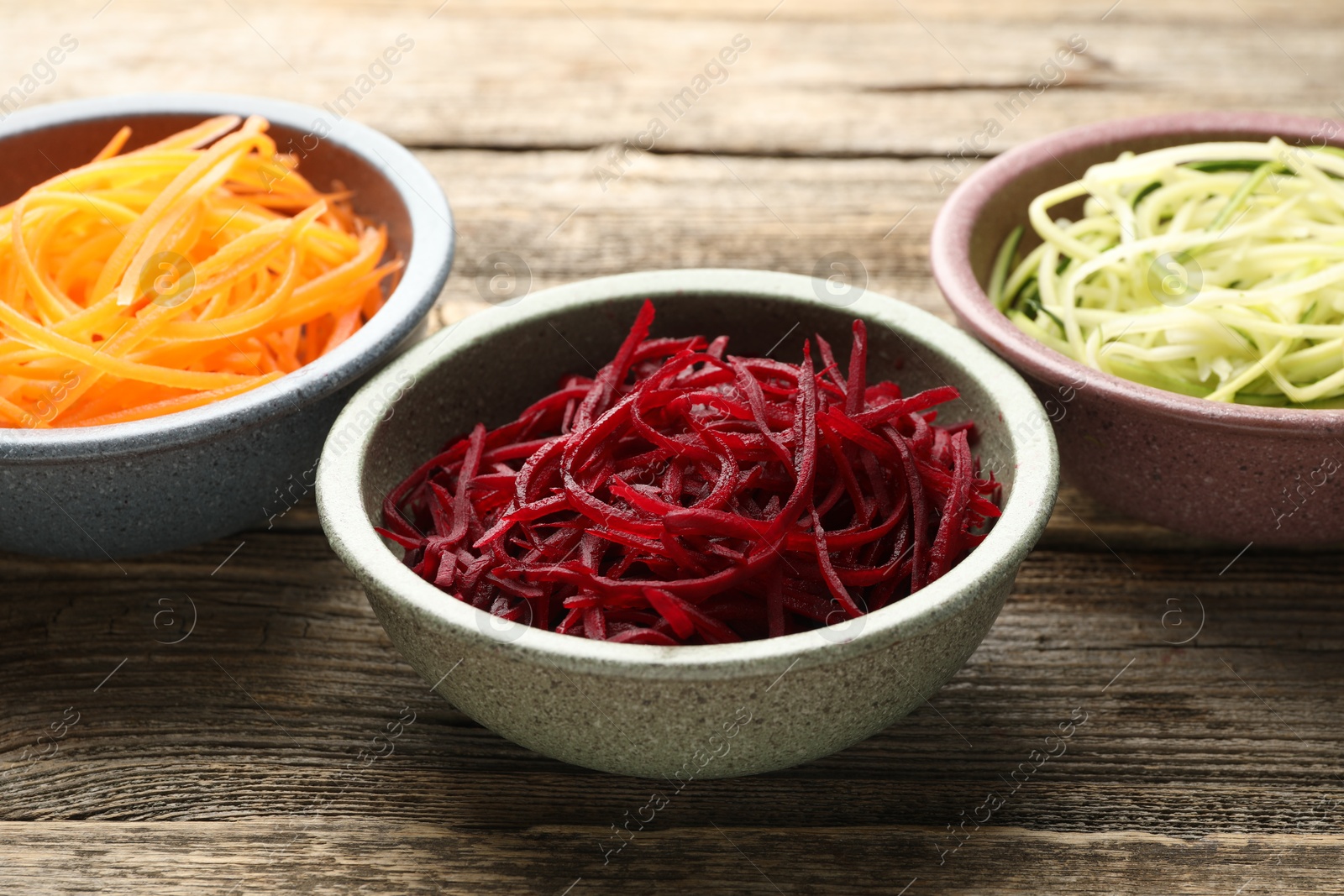 Different vegetable noodles in bowls on wooden table, closeup. Vegetarian dish Photo of Different vegetable noodles in bowls on wooden table, closeup. Vegetarian dish