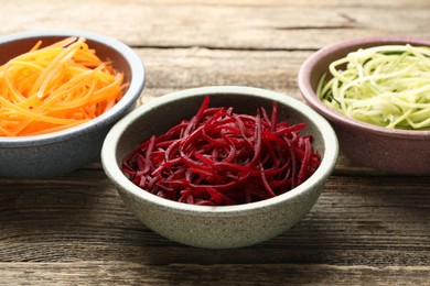 Photo of Different vegetable noodles in bowls on wooden table, closeup. Vegetarian dish