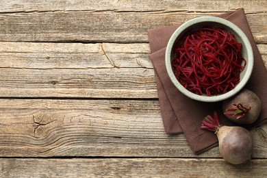 Photo of Vegetarian dish. Raw beetroot noodles and fresh vegetables on wooden table, flat lay. Space for text