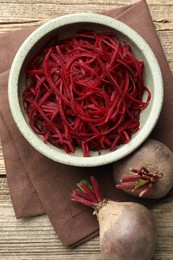 Photo of Raw beetroot noodles and fresh vegetables on wooden table, flat lay. Vegetarian dish