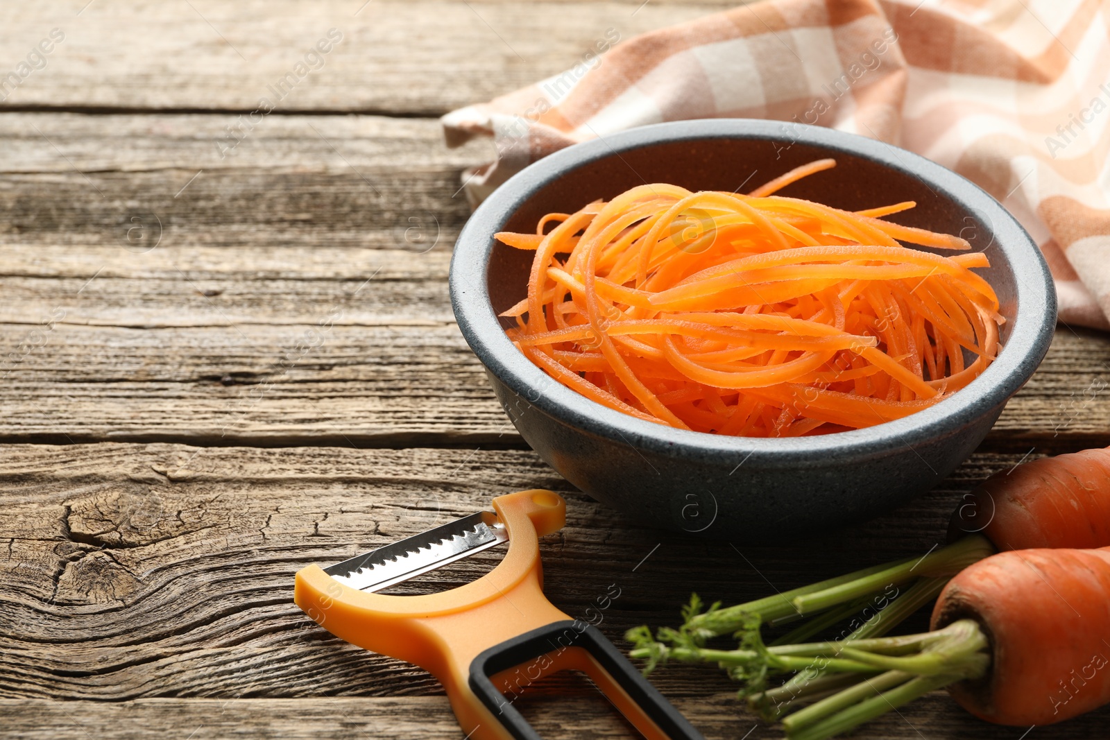 Vegetarian dish. Raw beetroot noodles, fresh vegetables and peeler on wooden table, closeup. Space for text Photo of Vegetarian dish. Raw beetroot noodles, fresh vegetables and peeler on wooden table, closeup. Space for text