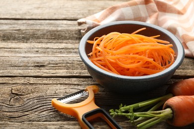 Photo of Vegetarian dish. Raw beetroot noodles, fresh vegetables and peeler on wooden table, closeup. Space for text