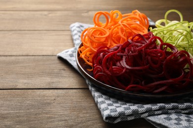 Photo of Vegetarian dish. Different vegetable noodles on wooden table, closeup. Space for text