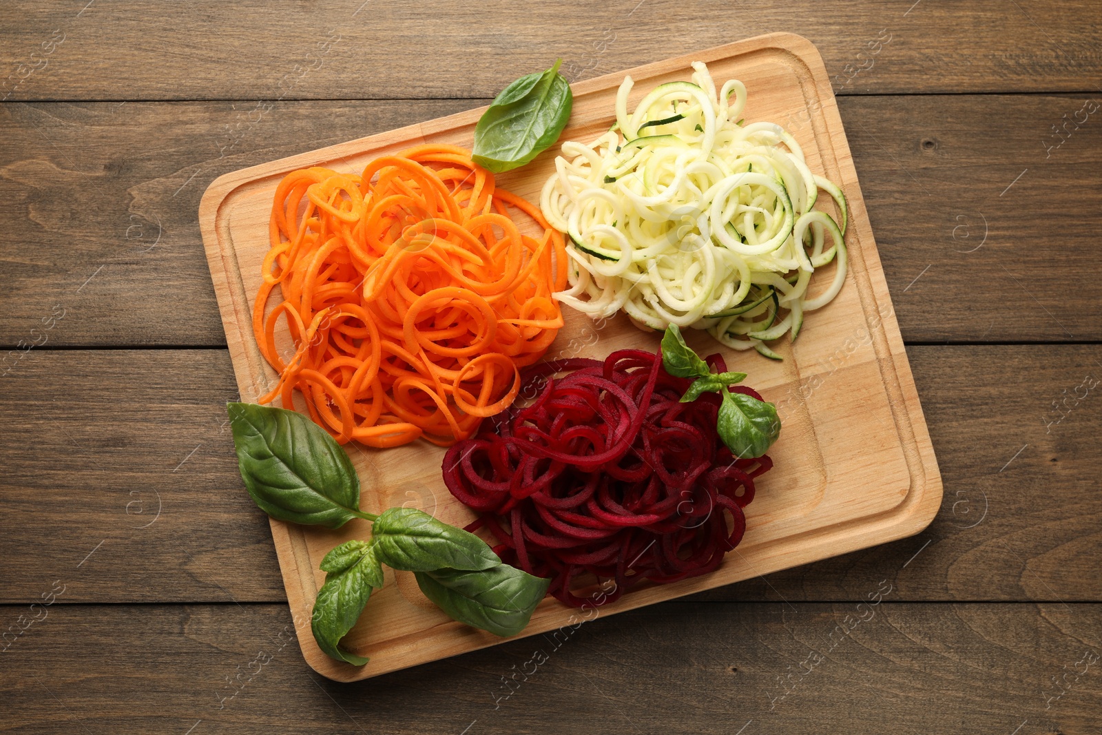 Different vegetable noodles with basil on wooden table, top view. Vegetarian dish Photo of Different vegetable noodles with basil on wooden table, top view. Vegetarian dish