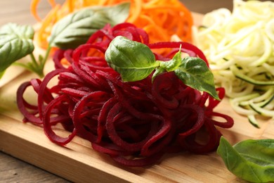 Photo of Different vegetable noodles with basil on table, closeup. Vegetarian dish