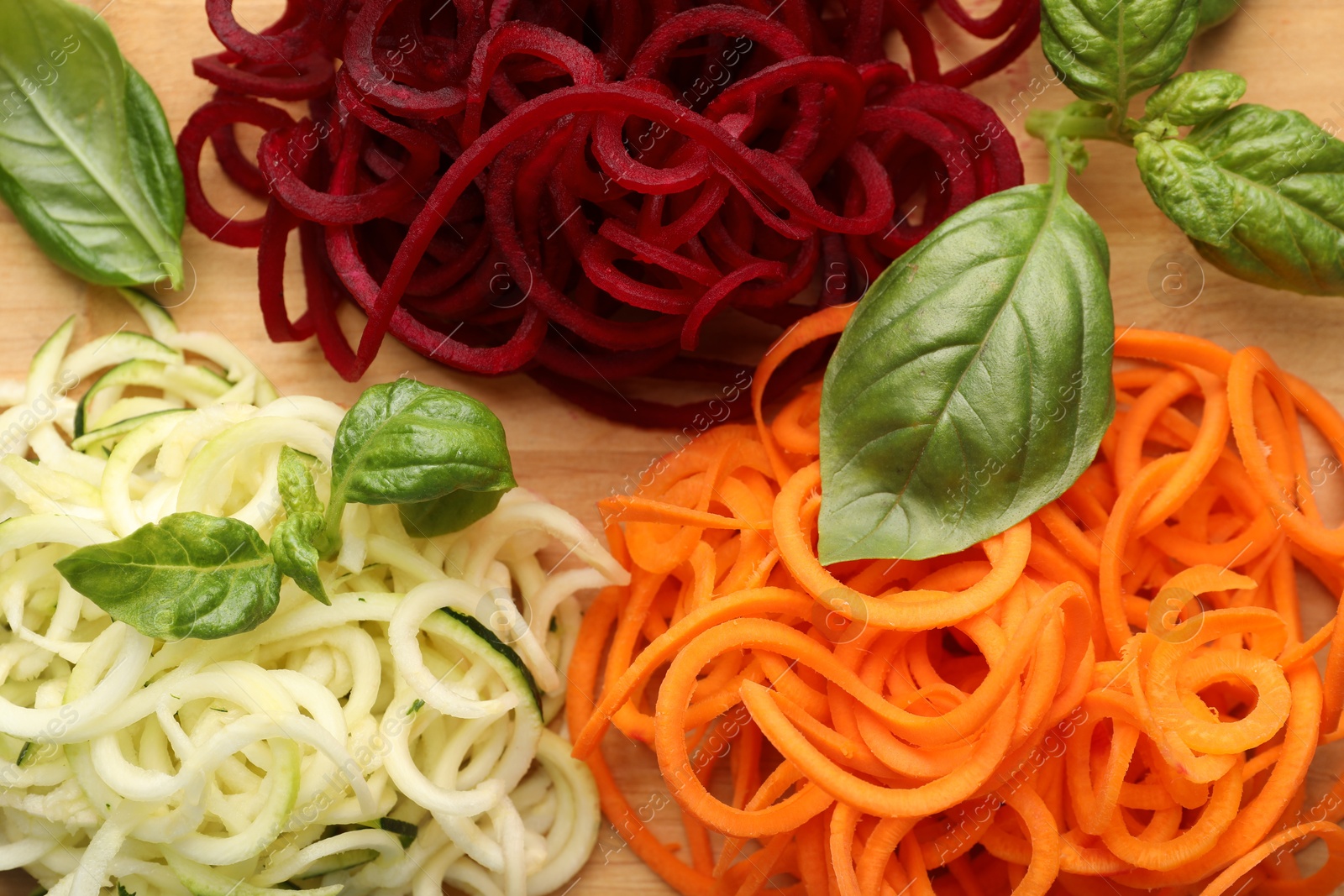 Different vegetable noodles with basil on wooden table, flat lay. Vegetarian dish Photo of Different vegetable noodles with basil on wooden table, flat lay. Vegetarian dish