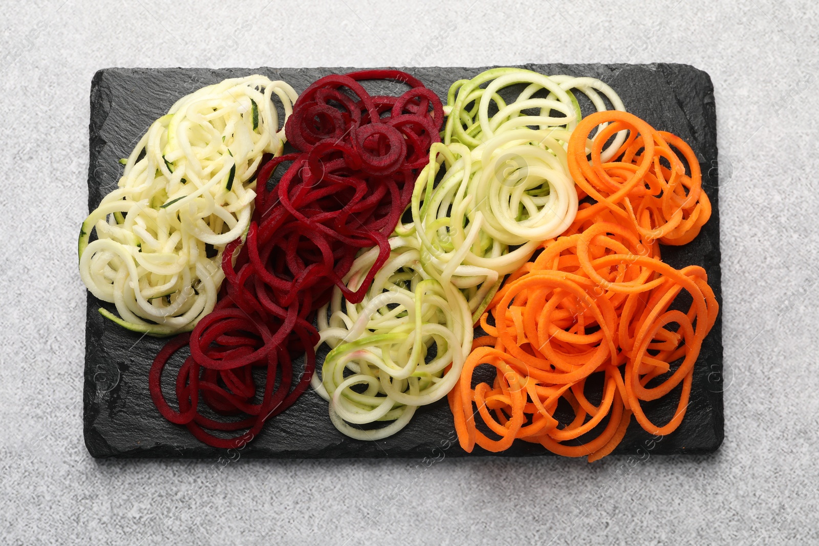 Photo of Different vegetable noodles on grey table, top view. Vegetarian dish