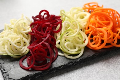 Photo of Different vegetable noodles on grey table, closeup. Vegetarian dish