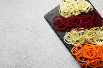 Photo of Vegetarian dish. Different vegetable noodles on grey table, top view. Space for text