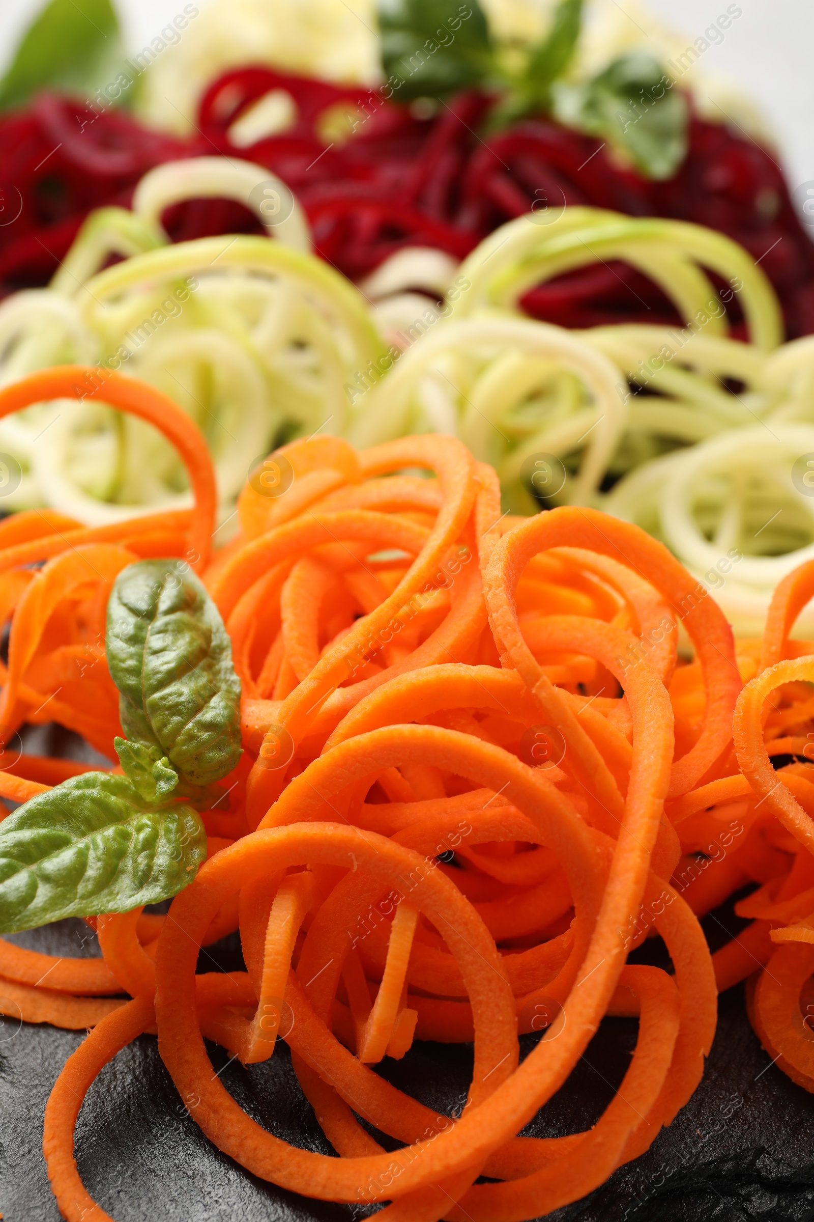 Different vegetable noodles with basil on table, closeup. Vegetarian dish Photo of Different vegetable noodles with basil on table, closeup. Vegetarian dish