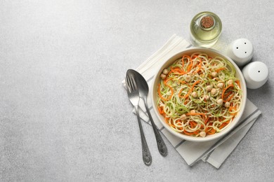Photo of Vegetarian dish. Tasty vegetable noodles with chickpeas served on grey table, flat lay. Space for text
