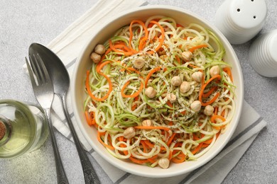 Photo of Tasty vegetable noodles with chickpeas served on grey table, flat lay. Vegetarian dish