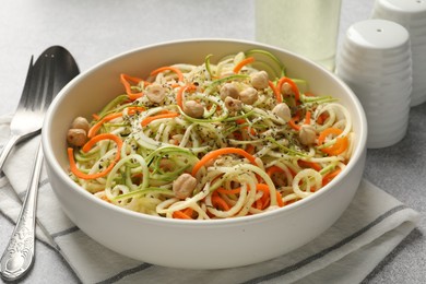 Photo of Tasty vegetable noodles with chickpeas served on grey table, closeup. Vegetarian dish