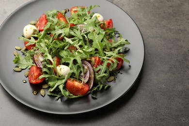 Photo of Tasty salad with arugula, mozzarella and vegetables on grey table, closeup. Space for text