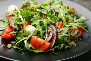 Photo of Tasty salad with arugula, mozzarella and vegetables on table, closeup