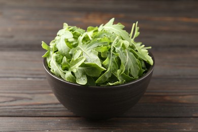 Photo of Fresh ripe green arugula leaves on dark wooden table, closeup