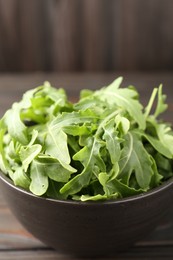 Photo of Fresh ripe green arugula leaves on dark wooden table, closeup