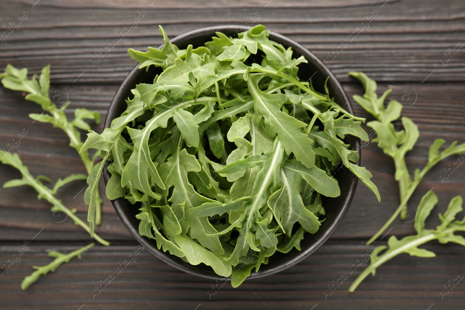 Fresh ripe green arugula leaves on dark wooden table, flat lay Photo of Fresh ripe green arugula leaves on dark wooden table, flat lay
