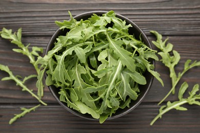 Photo of Fresh ripe green arugula leaves on dark wooden table, flat lay