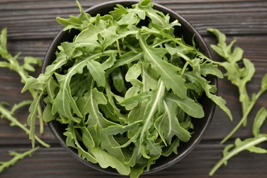 Photo of Fresh ripe green arugula leaves on dark wooden table, flat lay