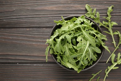 Photo of Fresh ripe green arugula leaves on dark wooden table, top view. Space for text